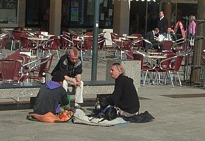 Obdachlose Menschen auf der Straße sitzend